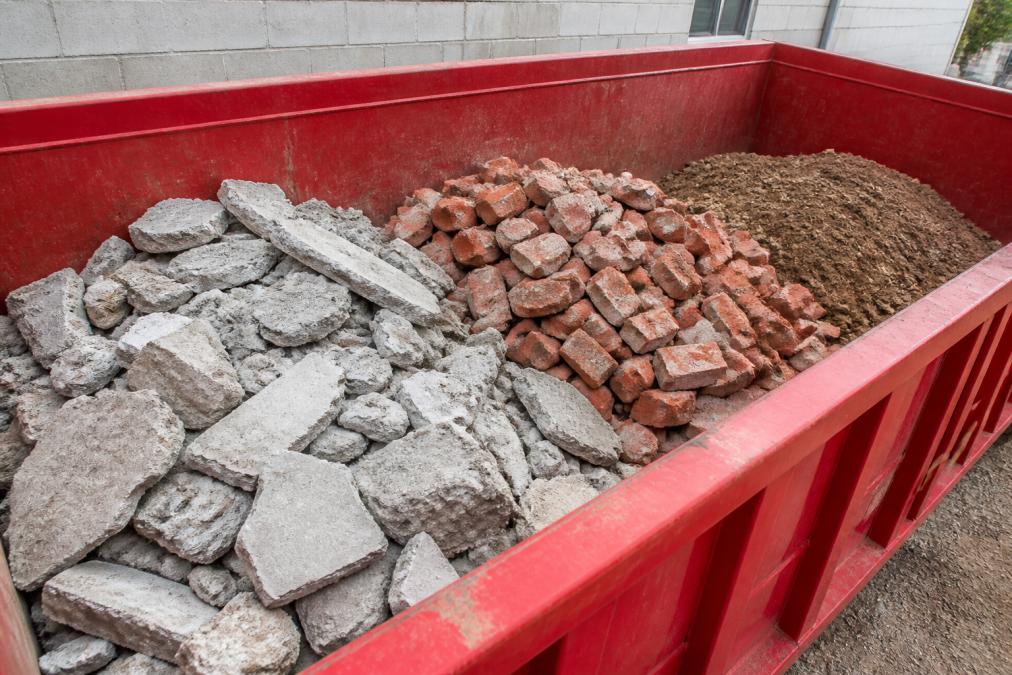 Close-up view of concrete chunks, bricks, and dirt materials neatly organized and ready for disposal in a 15-yard dumpster, showing proper material separation