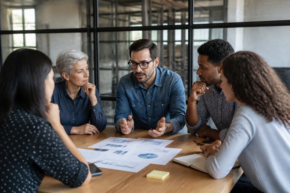 Sales team reviewing lead data and conversion metrics on multiple monitors in collaborative workspace, with dashboard displaying conversion rates and pipeline metrics