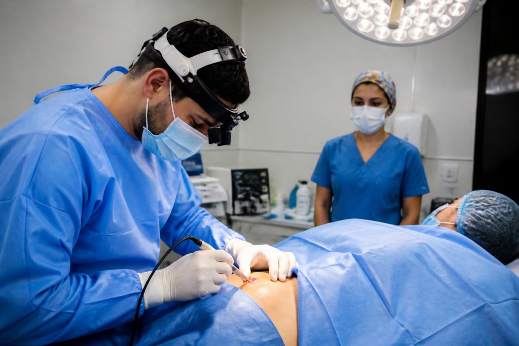 Consultorio médico moderno con equipamiento de electrocauterización visible, lámpara quirúrgica brillante, bandeja de instrumentos esterilizados, ambiente clínico limpio y profesional