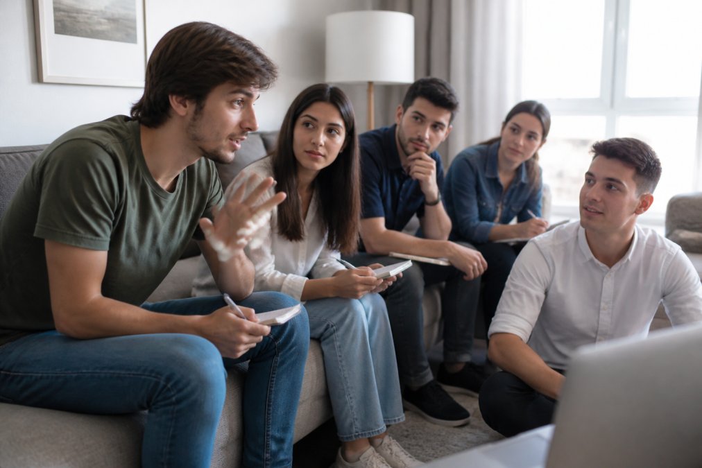 Grupo de estudiantes en una sesión de mentoría online, interactuando en una videollamada con instructor en ambiente colaborativo y de aprendizaje
