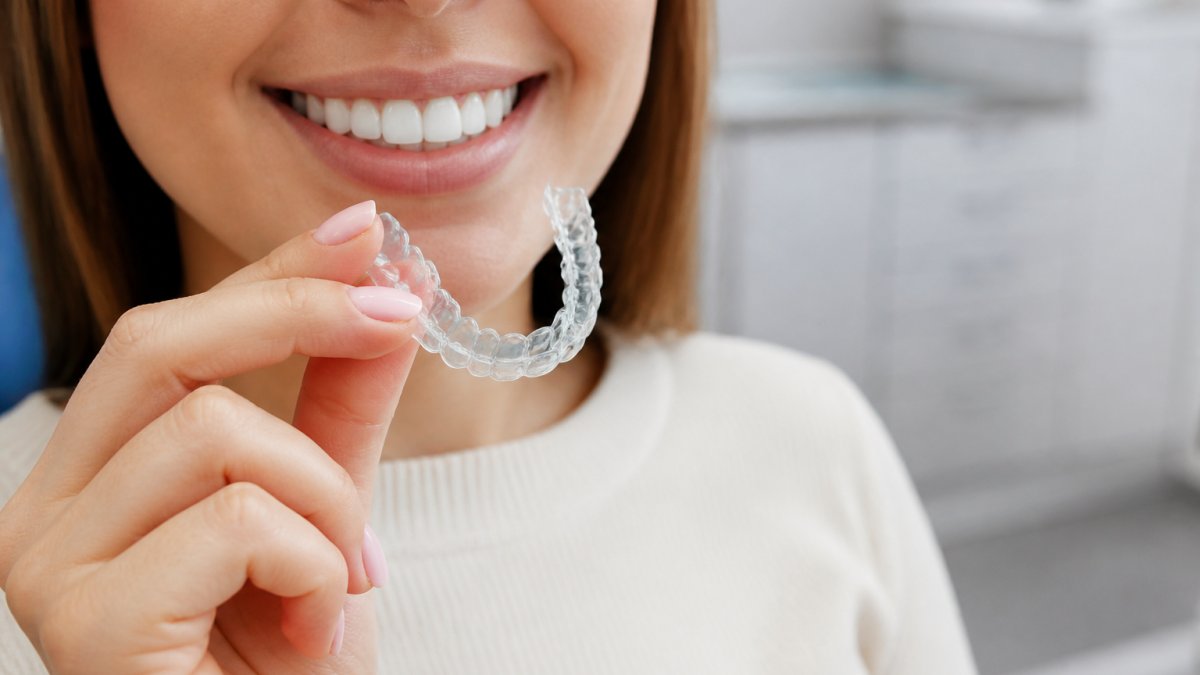 Patient inspecting clear aligner trays as effective alternatives to braces in a bright clinical setting