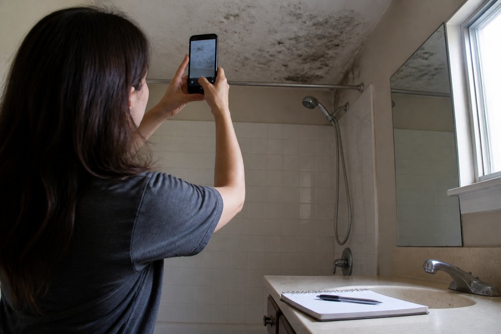 Renter photographing mold on a bathroom ceiling to document evidence before breaking your lease.