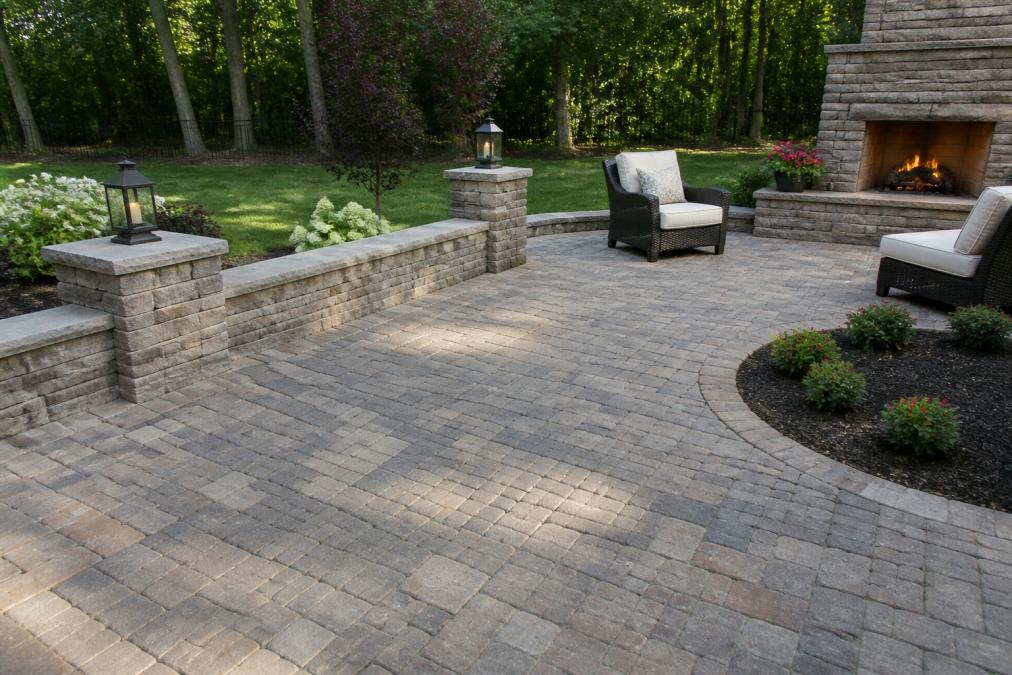 Completed residential patio with permeable pavers installed over geogrid and gravel base, showing finished surface with landscape integration and natural stone aesthetic