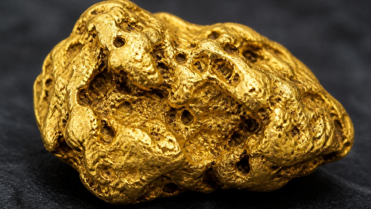 Close-up of a natural Australian gold nugget displaying organic surface texture, natural cavities, and distinct geological character against neutral background