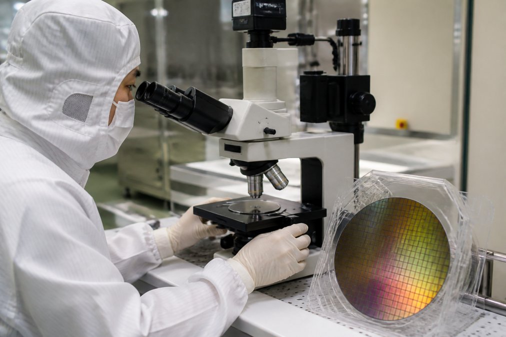 Semiconductor process engineer examining calibration wafer standards under optical microscope in fabrication facility, demonstrating precision measurement setup with proper lighting and magnification