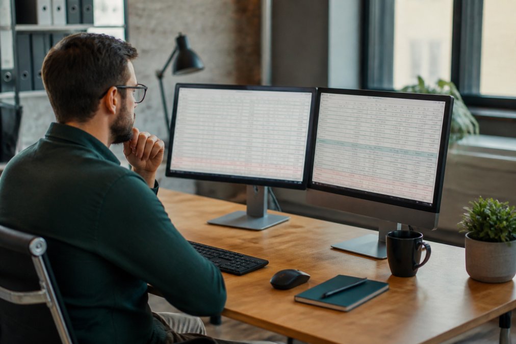 E-commerce business owner reviewing analytics dashboard on a computer screen showing sales trends and listing performance metrics in a modern office setting