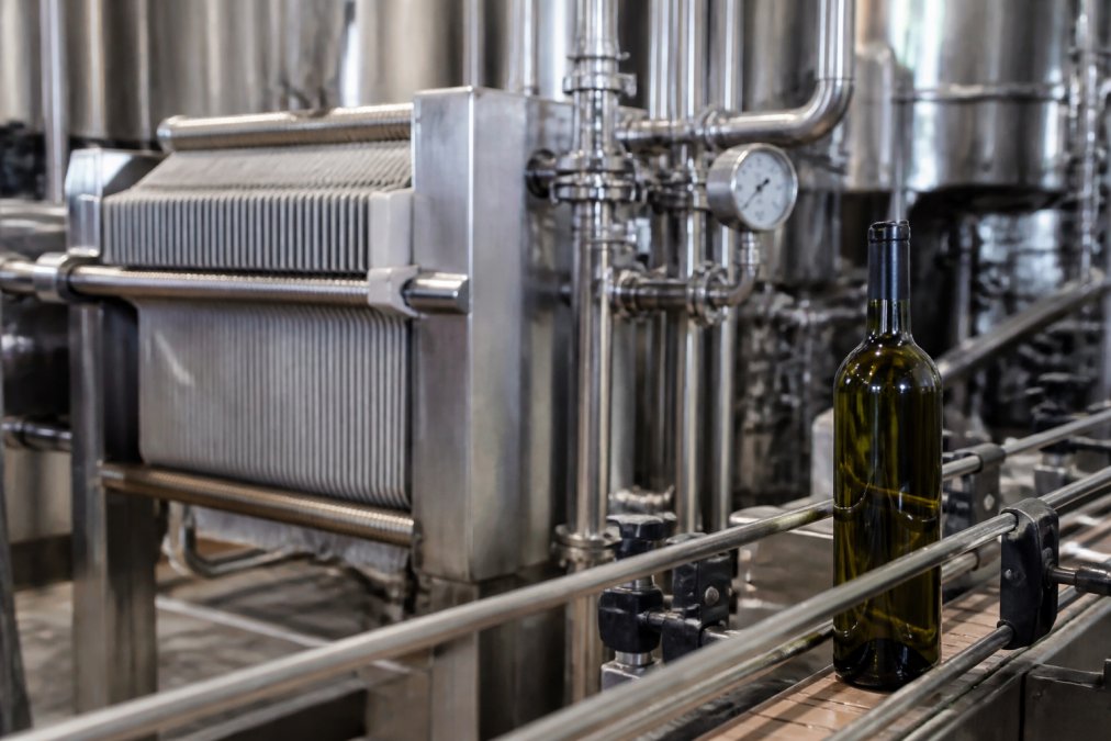 Moderne Produktionsanlage mit Vakuumfiltrationstechnik, Nahaufnahme von Filteranlage und Weinflasche in Produktionsumgebung mit professioneller Beleuchtung