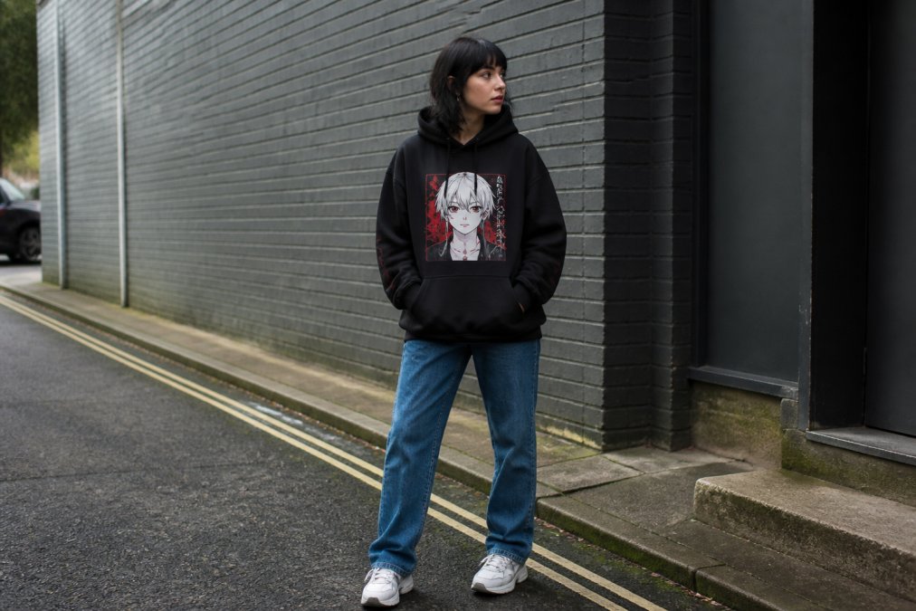 Young adult wearing an oversized anime streetwear hoodie with jeans and sneakers in an urban setting