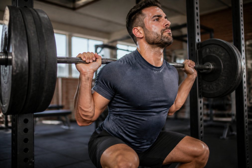 Person wearing anti-odor activewear during intense weightlifting session, showing sweat-dampened fabric with visible comfort and performance, natural gym lighting