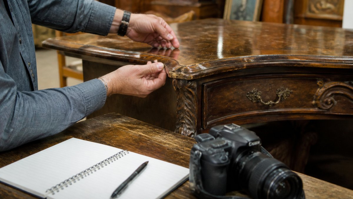 Step-by-step process for documenting damage on antique wooden furniture using a camera and a notebook