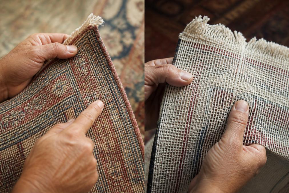 Close-up of hands examining the back of an antique Persian rug, revealing intricate hand-tied knots and visible warp/weft structure under natural window light
