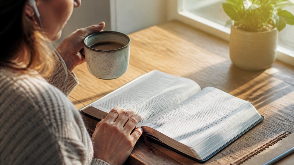 O persoană citește versetul zilei pe o aplicație biblică pe telefon, savurând o cafea într-o dimineață liniștită.