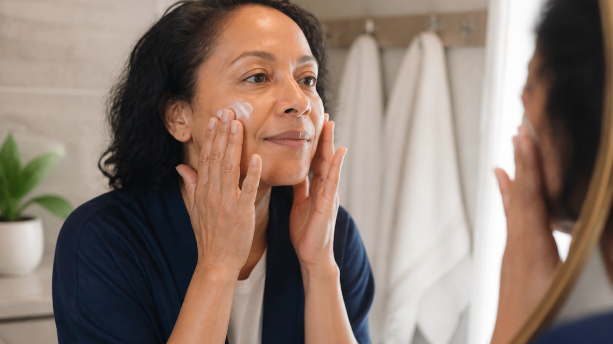 Woman's hands gently applying moisturizer to her face over clean skin with soft natural lighting, showing a calm, care-focused skincare moment
