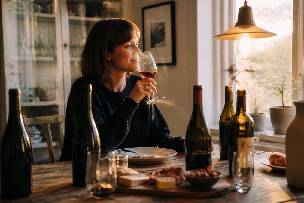 Person som njuter av ett glas naturvin vid ett bord fyllt med flaskor och visar att är naturvin bara för experter.