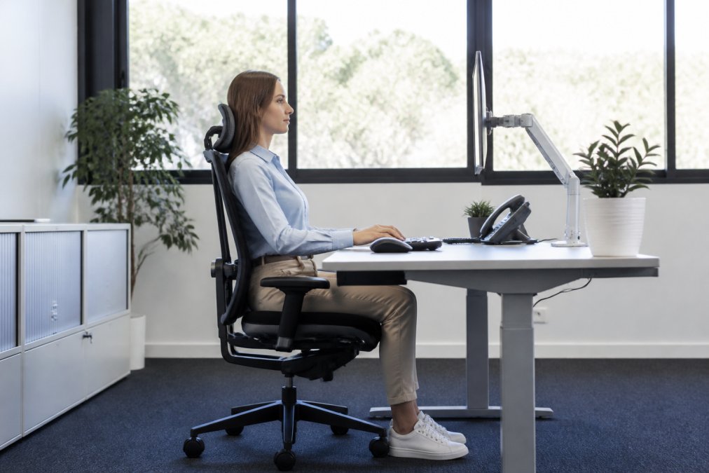 Mitarbeiter an einem ergonomischen Schreibtisch für mehr Arbeitssicherheit im Büro mit korrekter Sitzhaltung