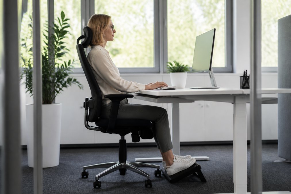 Mitarbeiter an einem ergonomischen Schreibtisch für mehr Arbeitssicherheit im Büro mit korrektem Monitorabstand.