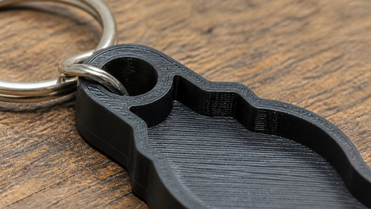 Close-up of a 3D-printed keychain with reinforced attachment hole and visible internal wall thickness, showing the structural details that prevent breakage under daily mechanical stress
