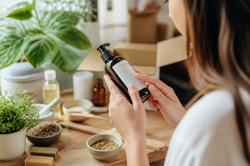Close-up of hands holding a skincare product bottle, examining the ingredient label with focused attention to product details and natural lighting