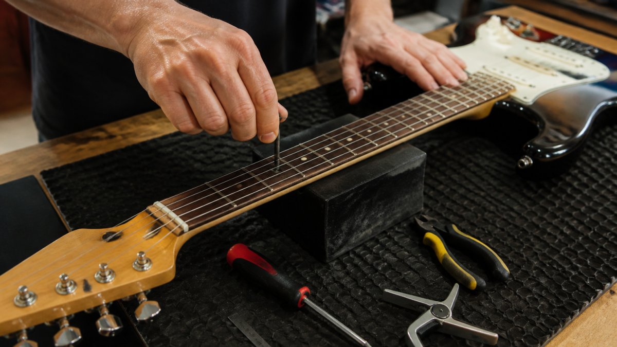 Musician adjusting the action and truss rod of budget guitars with tools on a workbench