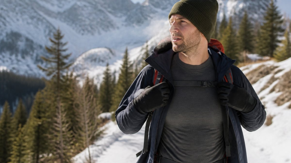Hiker wearing a fitted merino base layer under a shell jacket on a snowy mountain trail