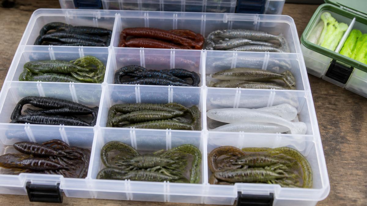 Organized tackle box with soft plastic baits in clear compartments, color-coded storage containers, and properly labeled sections showing multiple lure types neatly arranged