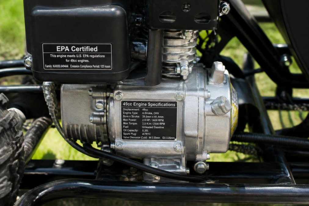 Close-up of a gas-powered go kart's 49cc engine showing the EPA certification label and manufacturer specifications plate mounted on the engine block with clear, legible text visible