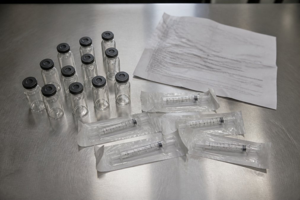 Unlabeled vials and syringes in generic peptide reconstitution kits on a stainless steel lab bench
