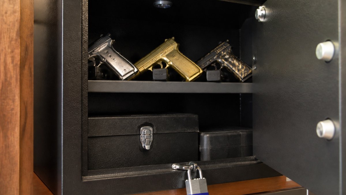 Locked drawer with novelty gun-shaped lighters secured on a high shelf inside a metal safe, with a padlock visible and childproofing measures in place