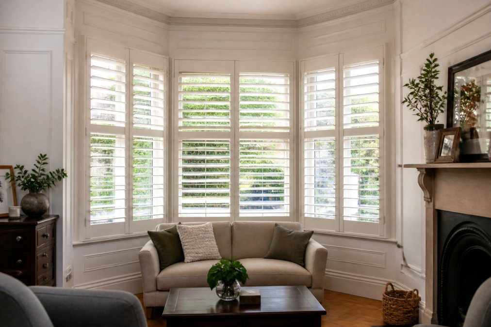 Infographic showing why plantation shutters worth it, detailing light control and wood finish in a period bay window room.