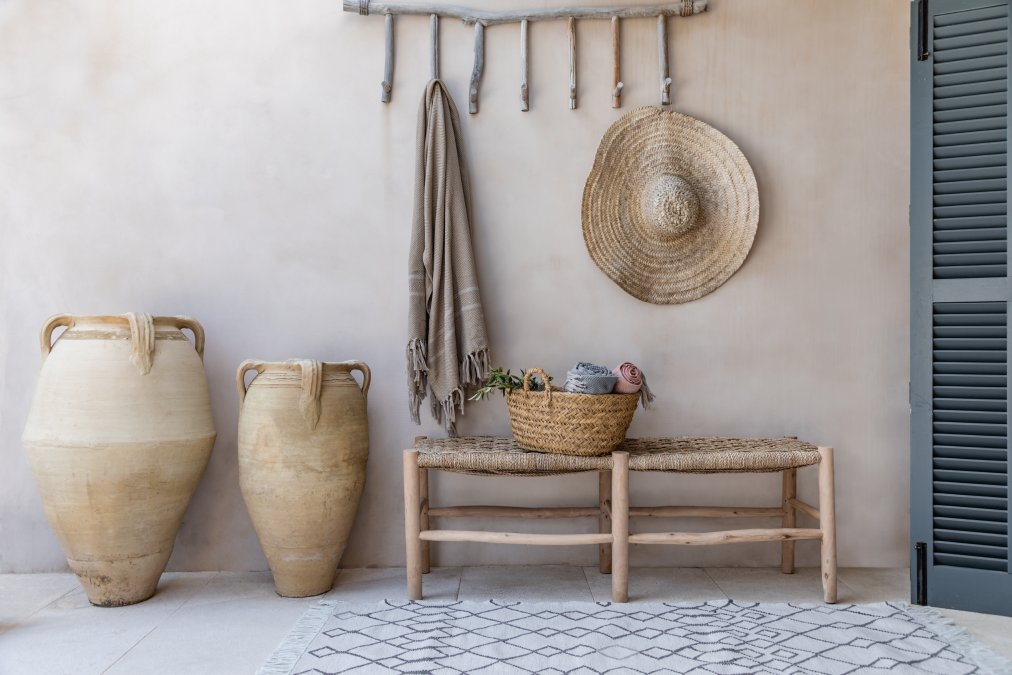 Recycled Berber style rug in off white and charcoal with tasseled ends in front of to of bench with mediterranean pots