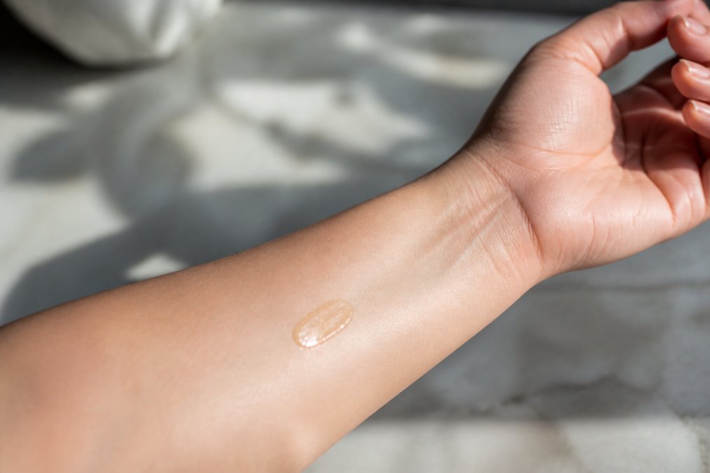 Person's wrist with small fragrance sample applied to clean skin, showing proper patch testing placement with natural daylight on arm