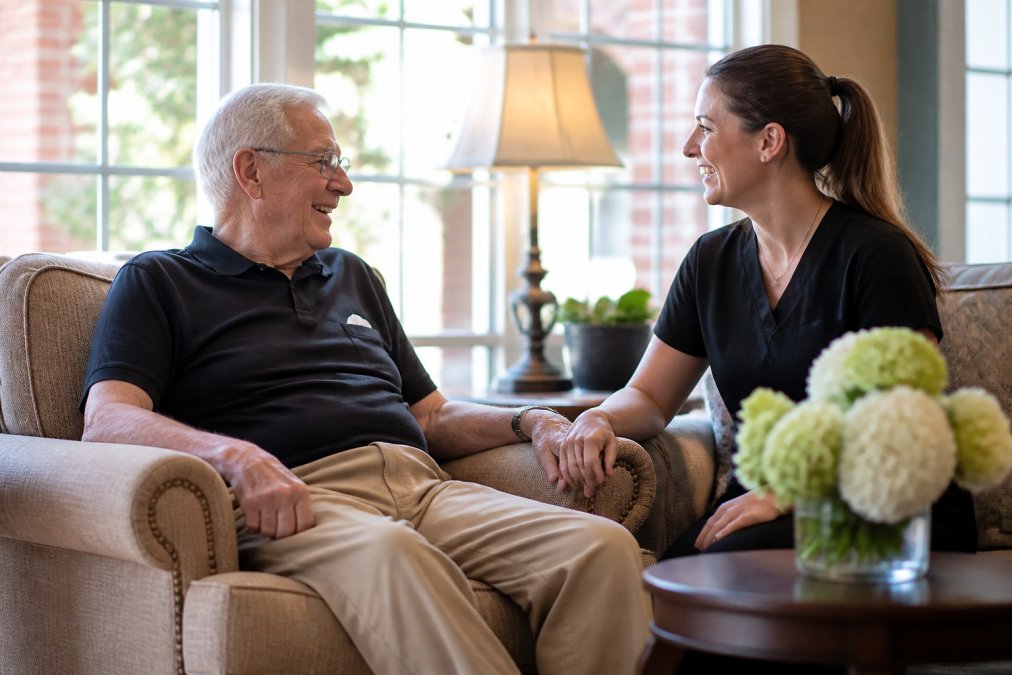 Senior veteran smiling while talking with staff in a bright assisted living for veterans common area
