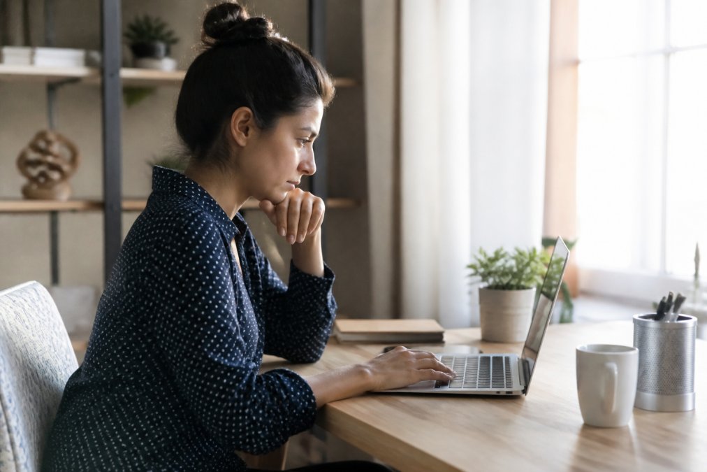 Person sitting at a desk reviewing personal privacy settings on a laptop for identity monitoring purposes.