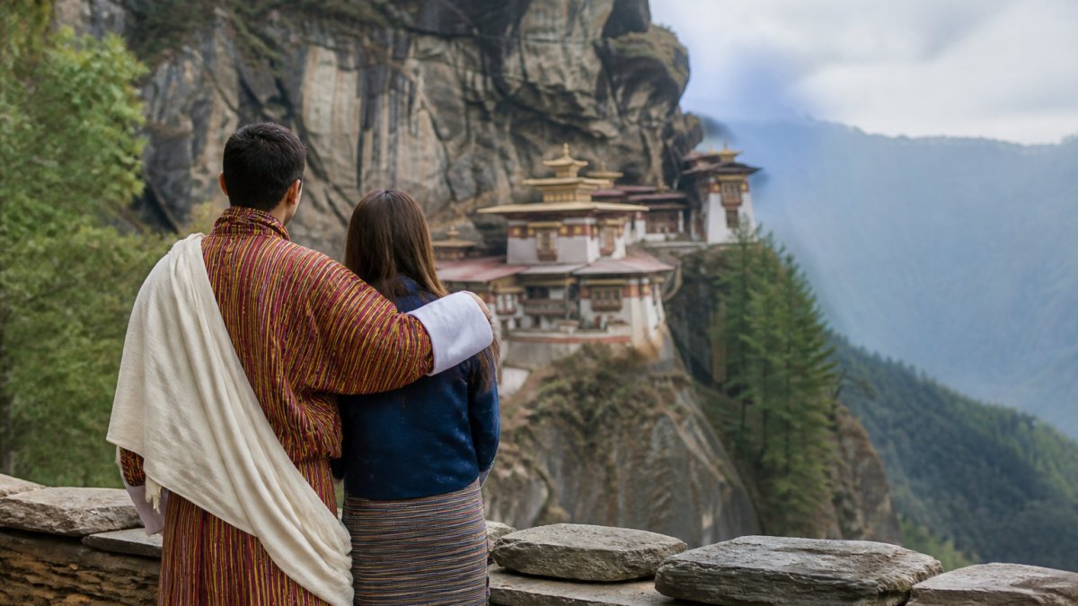 A couple standing together while overlooking the majestic mountain landscapes during their Bhutan experiences.