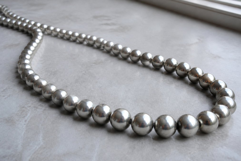 Close-up of authentic mustang silver pearls necklace showing individual bead detail, smooth finish, and consistent symmetry under natural window lighting