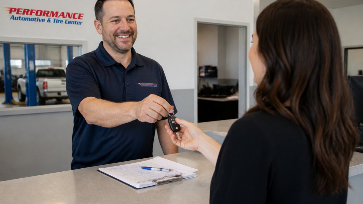 A customer service advisor at an auto repair shop handing car keys to a customer in a clean, well-lit service center lobby