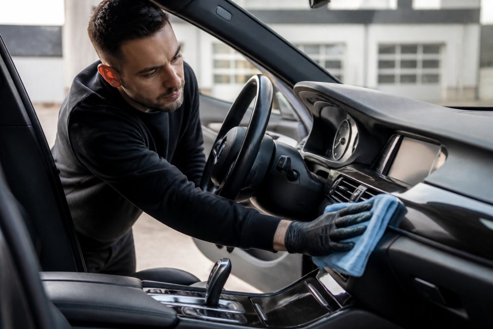 Interieur van een auto wordt gereinigd met microvezeldoeken, stuurwiel en dashboard zichtbaar, schoon en glanzend uiterlijk, natuurlijk licht