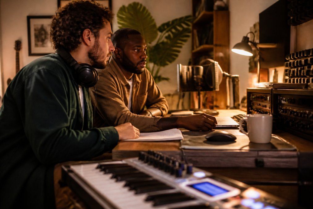 Music producer reviewing waveform data and music metadata on dual monitors in a studio