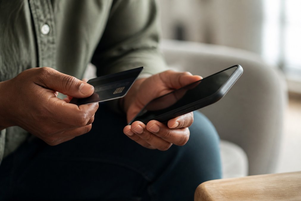Gros plan d'une main tenant une carte de crédit près d'un téléphone intelligent affichant une interface de paiement sécurisé