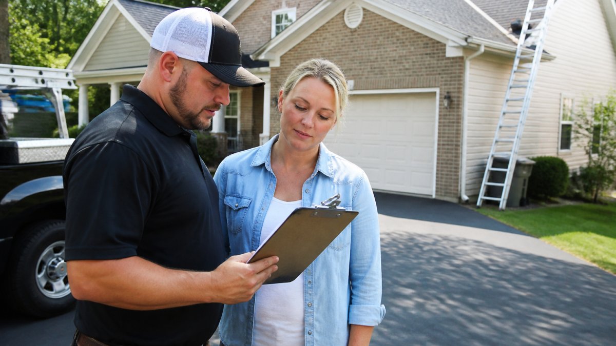 Roofing contractor reviewing a written estimate for the average cost of roof replacement 2026 with a homeowner.
