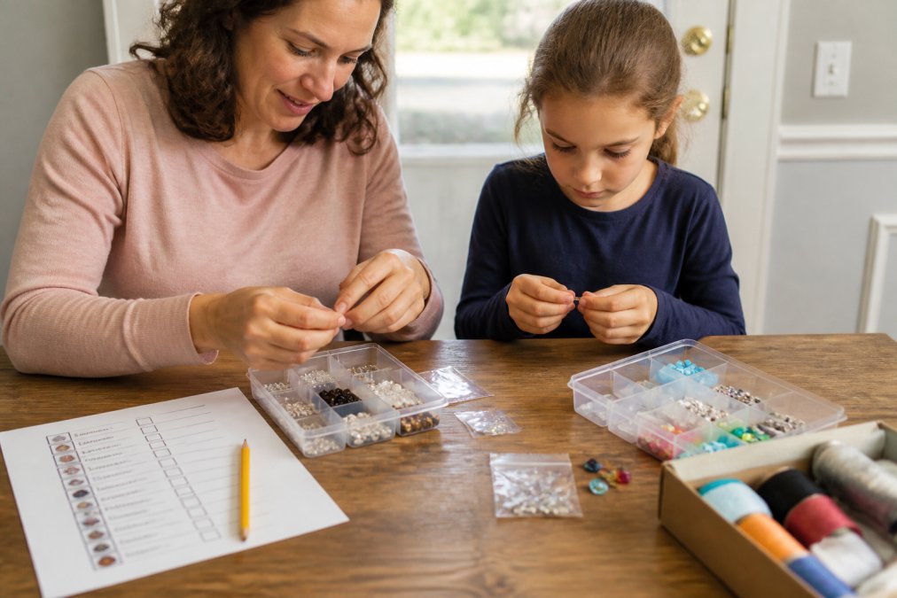 A parent and child using a checklist to organize craft components and identify missing pieces in clear trays.