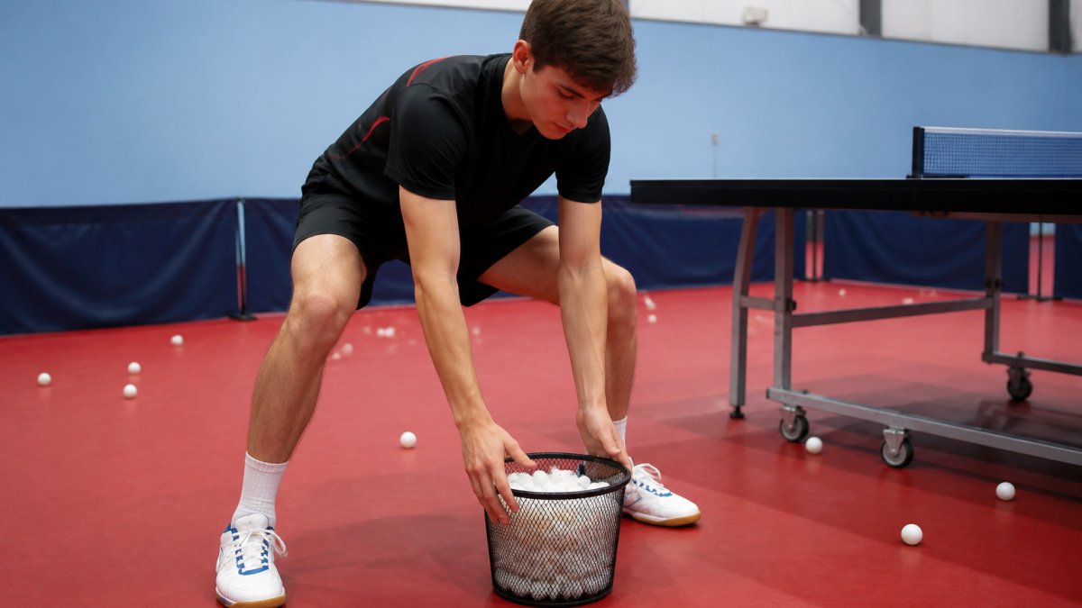 Person in a gym demonstrating a back friendly lifting stance with feet shoulder-width apart and knees bent.