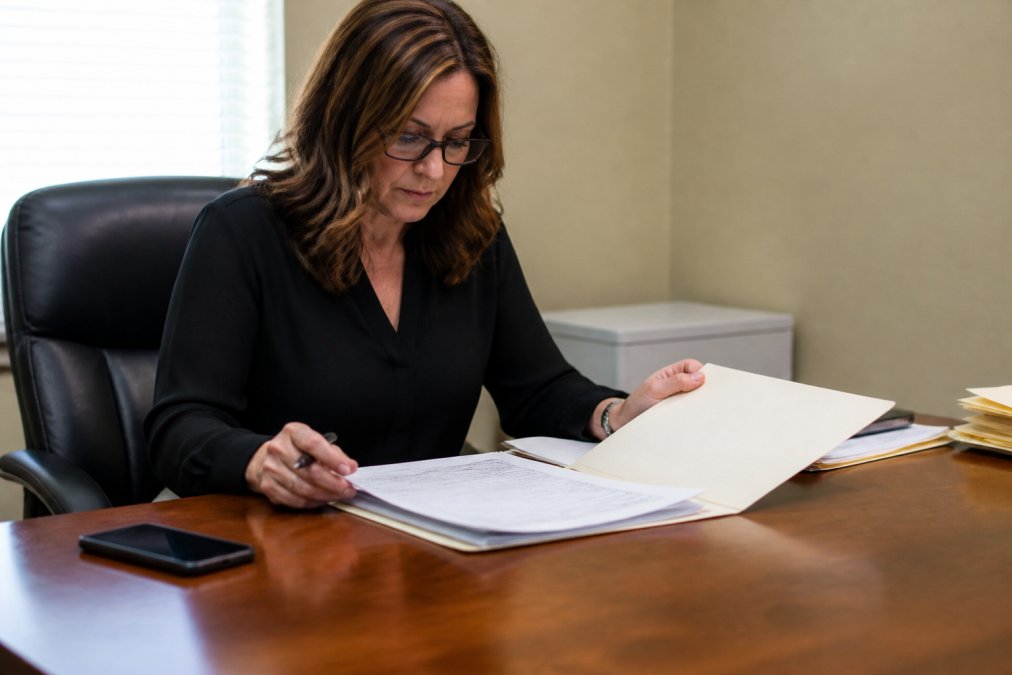 Person sitting at a desk reviewing bail bond paperwork with a pen and phone in a bright office setting
