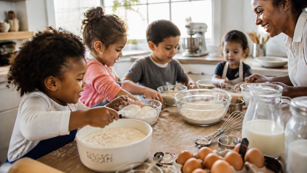 A diverse group of toddlers and young children of different ages and ethnicities, including Black children, actively engaged in baking together in a bright home kitchen. Some are scooping flour, others pouring ingredients into bowls, and an adult supervises nearby. ### Scooping, Pouring, and Measuring Scooping builds hand strength and teaches cause-and-effect. Pouring develops hand-eye coordination, start with small amounts for success. Measuring teaches counting and spatial awareness; even 2-year-olds can learn "one scoop" or "two scoops." **Try these activities:** - Scoop dry ingredients into a bowl using a large spoon - Pour ingredients from a small container into a larger one - Use a measuring cup to fill a bowl - Practice leveling off a measuring cup with a butter knife ### Mixing, Stirring, and Rolling Mixing engages both hands and builds shoulder strength. Stirring requires sustained grip and circular motion, hold the bowl steady while your toddler stirs. Rolling dough between their palms develops hand strength and finger dexterity. **Try these activities:** - Stir dry ingredients with a wooden spoon - Mix soft dough with their hands (supervised) - Roll small dough balls between their palms - Press dough flat with their fingers or a rolling pin ### Pinching, Sprinkling, and Spreading Pinching is one of the most important fine motor skills, the exact motion needed for holding a pencil later. Sprinkling teaches control and precision, requiring a gentler hand and careful aim. Spreading builds wrist control and hand-eye coordination. **Try these activities:** - Pinch chocolate chips or sprinkles onto dough - Sprinkle cinnamon or sugar onto a surface - Spread soft frosting or dough with a butter knife - Place toppings one at a time onto cookies ## Fine Motor Activities for Toddlers by Skill Level Not all toddlers develop at the same pace. Here's how to match [baking activities