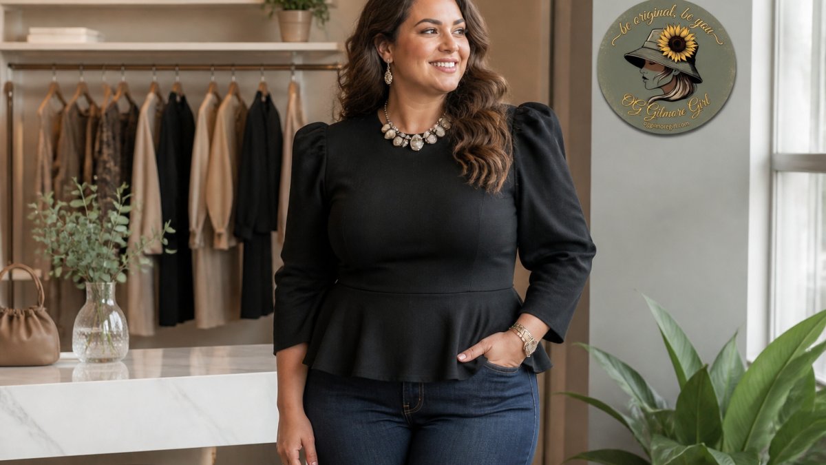 Woman wearing a statement necklace and structured top with shoulder pads, standing confidently to demonstrate upper body styling for pear shape balance, natural studio lighting