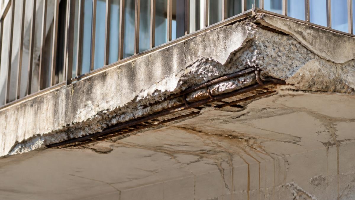 Concrete balcony surface with cracks and exposed steel needing balcony waterproofing repairs.