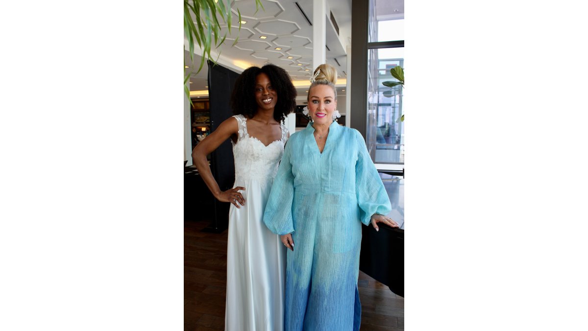 A woman wearing an elegant blue ombré organza jumpsuit with dramatic balloon sleeves at a chic evening event, holding a glass of champagne while conversing with guests under warm ambient lighting