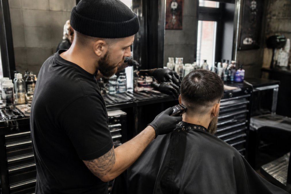 Professional barber using high-quality clippers and trimmers on a client in a well-organized barbershop station with organized equipment displays