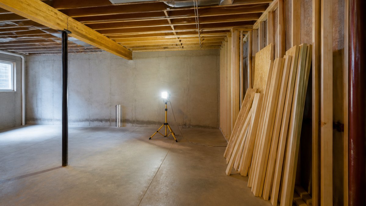 Unfinished basement with exposed joists and lumber ready for a basement remodel project
