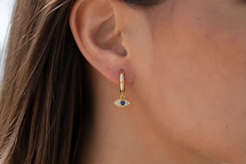 Close-up of a woman wearing a sterling silver evil eye necklace with vibrant blue and green enamel detail, showcasing the intricate craftsmanship and pendant clarity in natural daylight